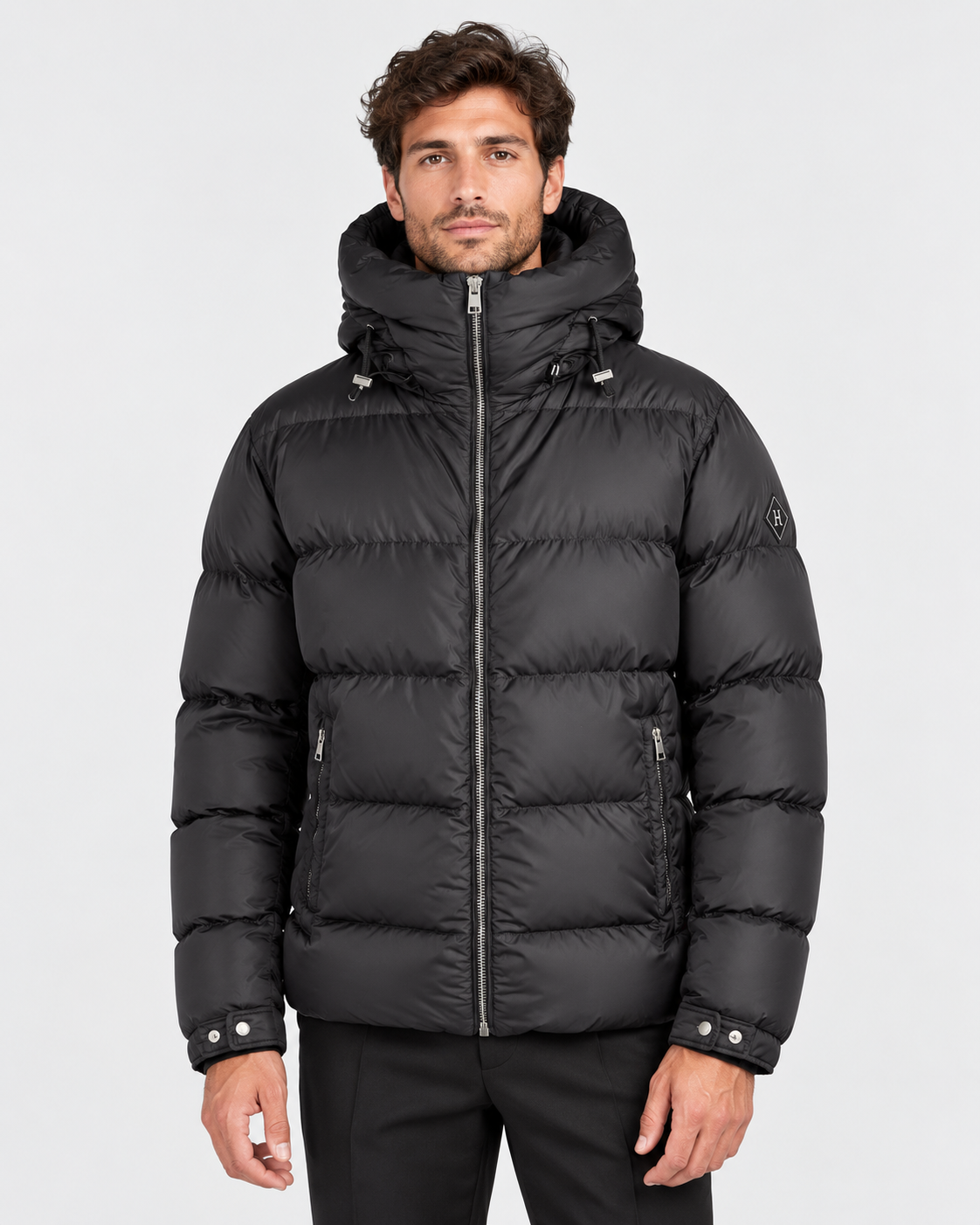 Piumino Herno nero da uomo indossato, con cappuccio, trapuntatura orizzontale e tasche con zip, visto frontalmente.