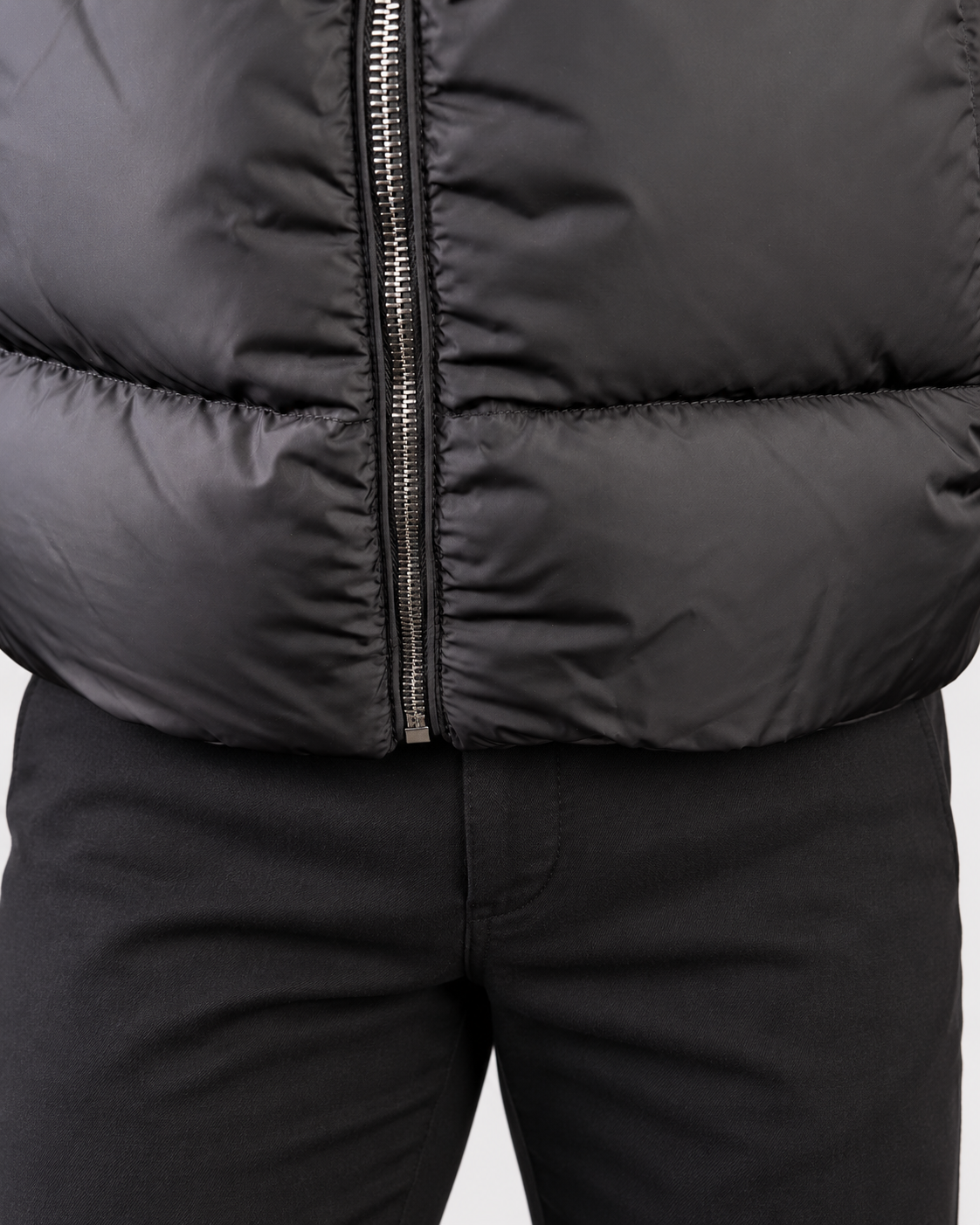 Dettaglio della zip frontale e del fondo del piumino Herno nero con trapuntatura orizzontale.